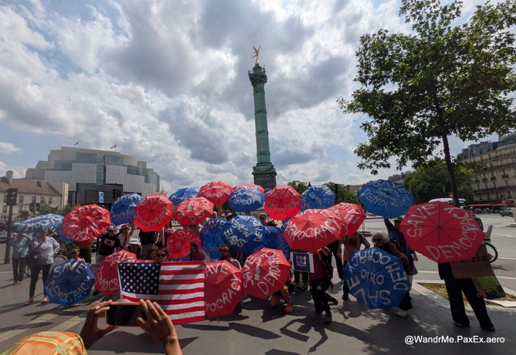Red and blue umbrellas representing many of the 50 US states, working to save democracy in front of La Bastille in Paris during the No Kings protest